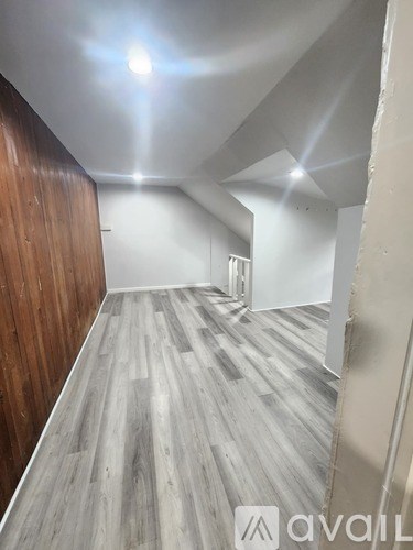 A room with wooden flooring and a white wall.