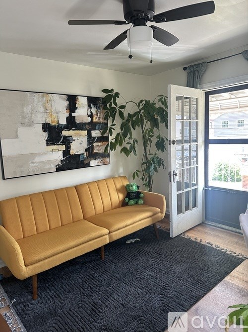 A living room with a yellow couch and a ceiling fan.