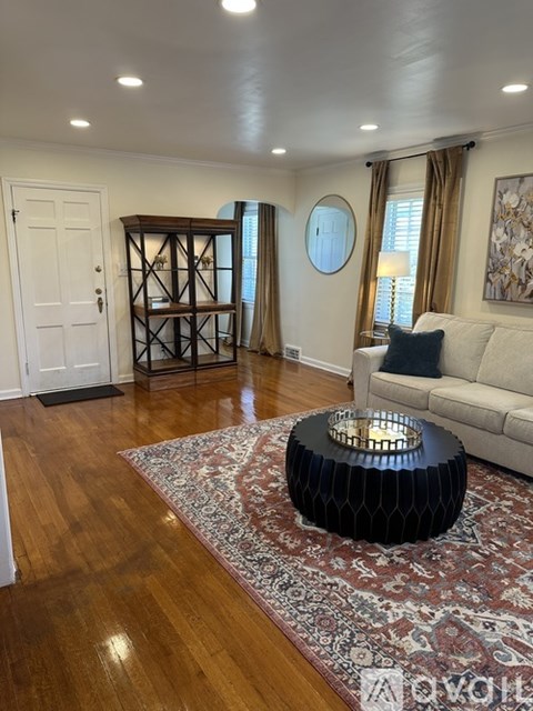 A living room with a white couch and a large round mirror on the wall.