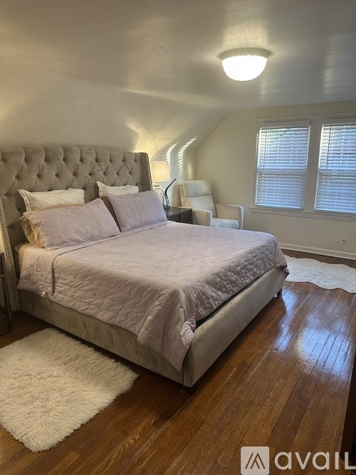 A bedroom with a bed, a chair, and a rug.