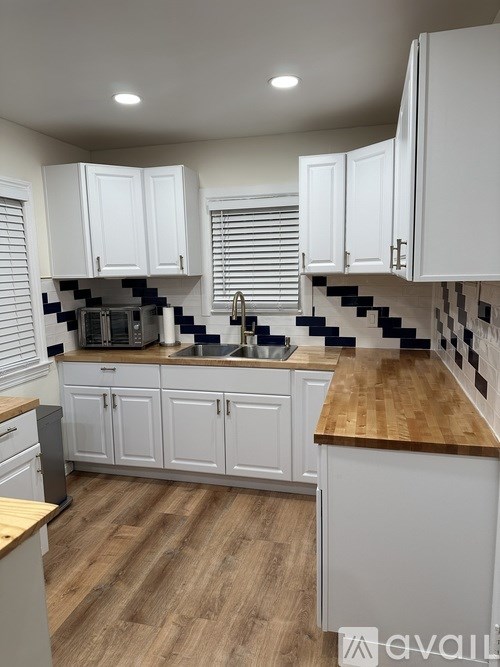 A kitchen with white cabinets and a wooden counter top.