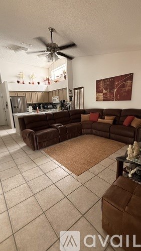 A living room with a brown couch and a ceiling fan.
