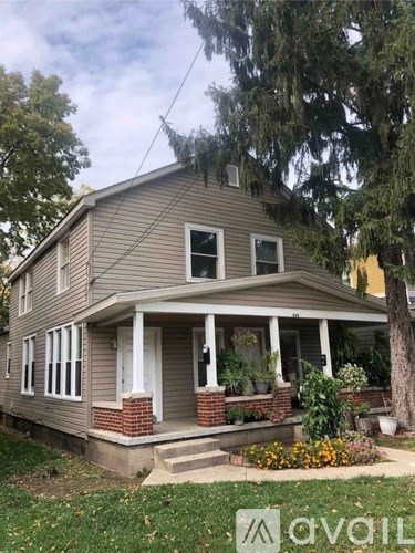 A house with a front porch and a tree in front.