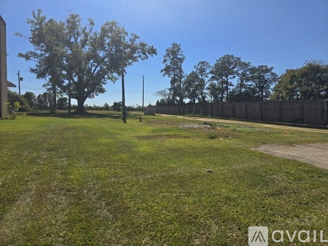 A grassy field with a fence and trees in the distance.