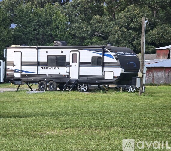 A white and black RV with the word "PROWLER" on the side is parked in a grassy area.
