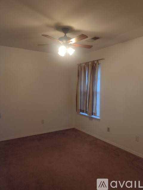 A room with a ceiling fan and a window with curtains.