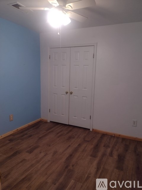 A room with a white door and wooden flooring.