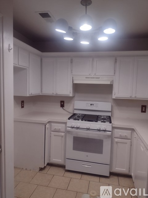 A kitchen with white cabinets and a white stove top oven.