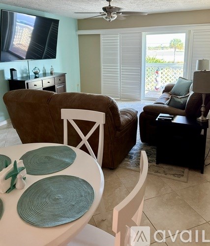 A living room with a brown couch, a white chair, and a dining table with green plates on it.