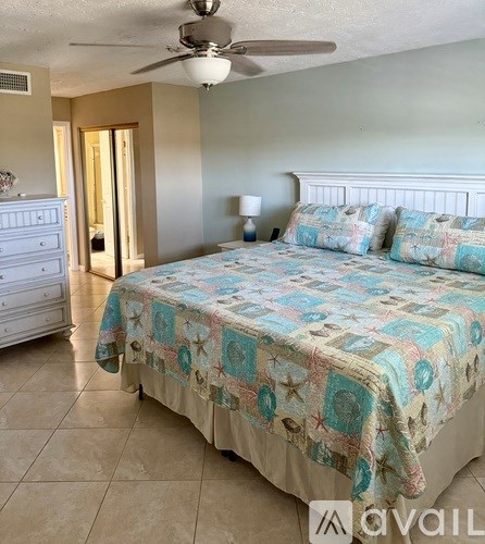 A bedroom with a bed, dresser, and ceiling fan.