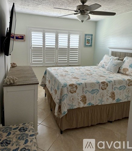 A bedroom with a bed, dresser, and ceiling fan.