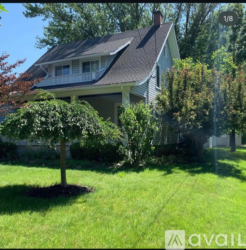 A house with a green lawn and a tree in front of it.