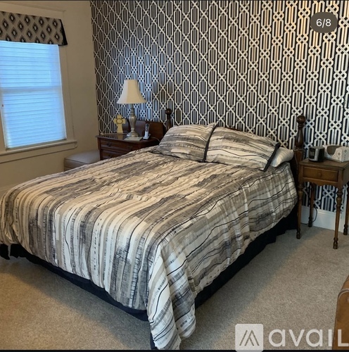 A bedroom with a bed, nightstand, and lamp.