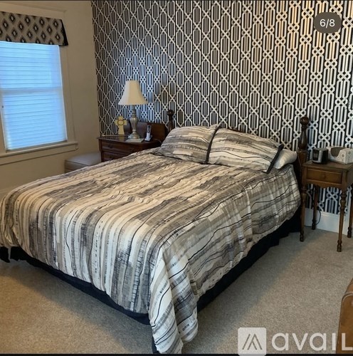 A bedroom with a bed, nightstand, and lamp.