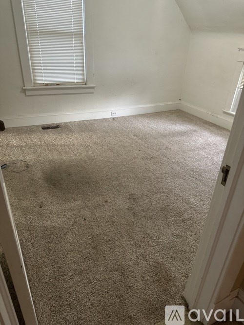A carpeted room with a window and a door.
