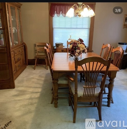 A wooden dining table with chairs and a flower arrangement on it.