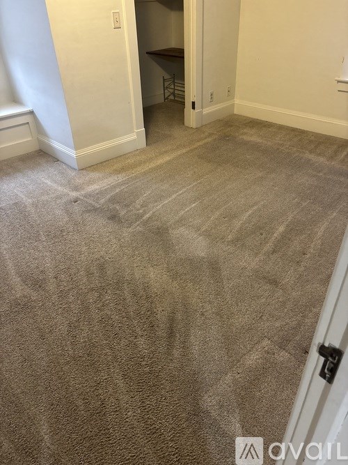 A carpeted room with a doorway leading to another room.