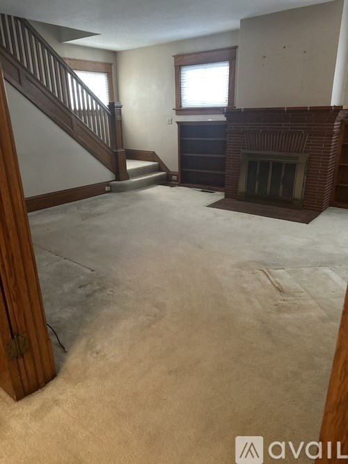 A living room with a fireplace and a staircase.