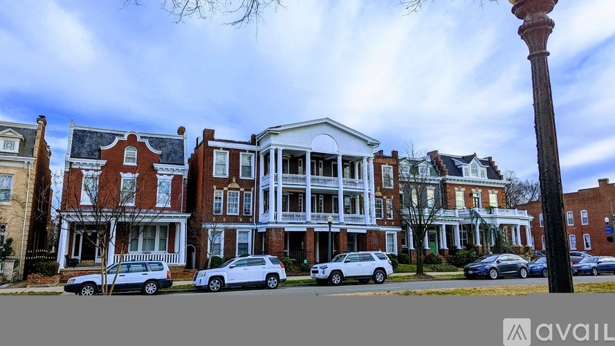A row of houses with cars parked in front.