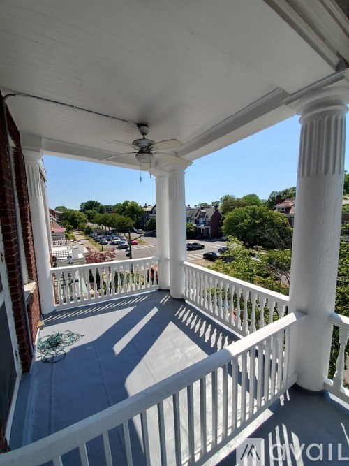 A balcony with white railings and a ceiling fan.