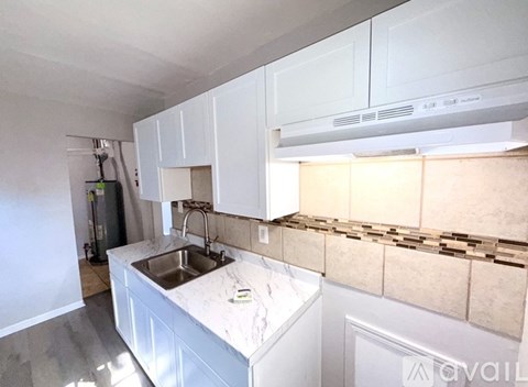 A kitchen with white cabinets and a marble countertop.