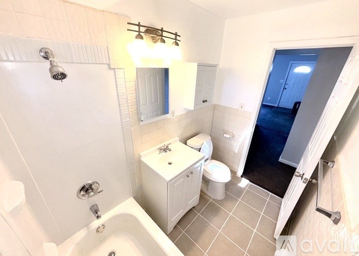 A small bathroom with a white tub, toilet, and sink.