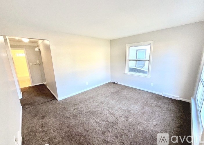 A room with a carpeted floor, a window, and a door.