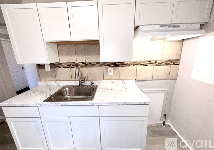 A kitchen with white cabinets and a marble countertop.