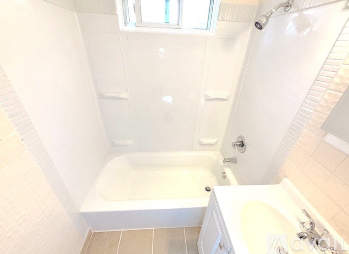 A white bathroom with a tub, sink, and shower.