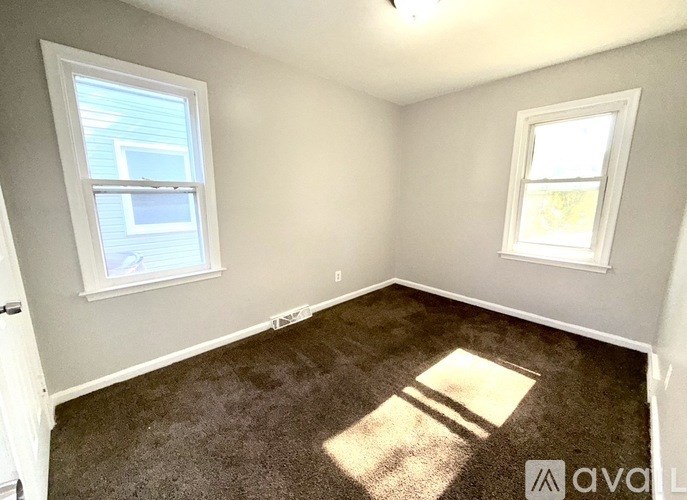 A room with two windows and a carpeted floor.