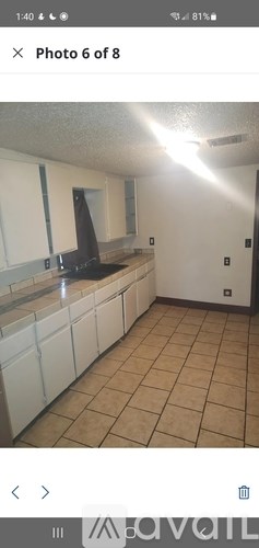 A kitchen with white cabinets and a black countertop.