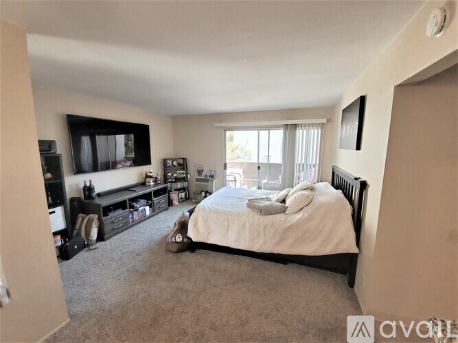 A bedroom with a bed, a television, and a window.