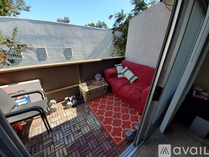 A balcony with a red couch and a chair.