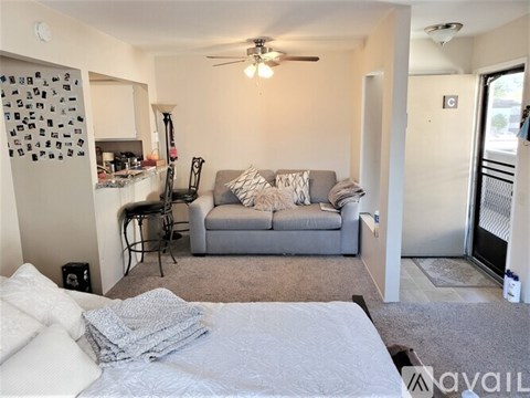 A living room with a grey couch and a white bed.