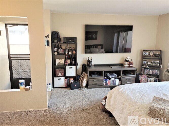 A bedroom with a bed, a TV stand, and a shelf with various items.
