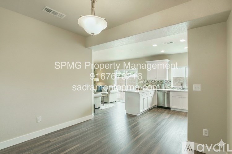 A well-lit, spacious kitchen and living room with wood flooring and white walls.