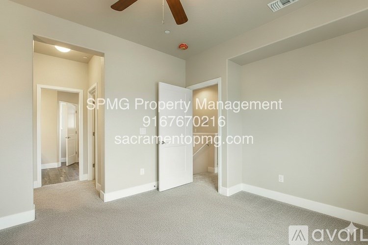 An empty room with a fan and a doorway leading to another room.