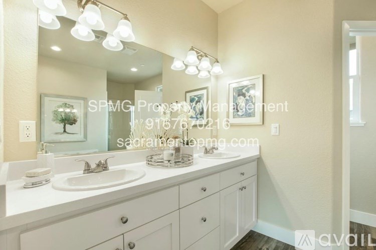 A bathroom with a large mirror and lights above it.