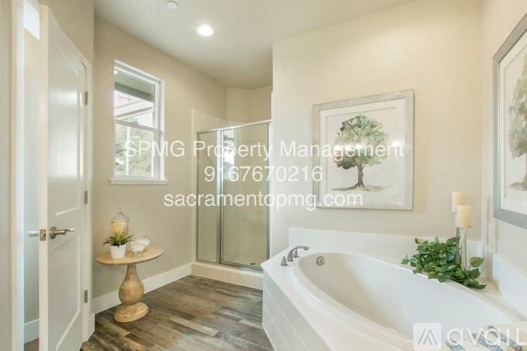 A bathroom with a tub, a table, and a painting on the wall.