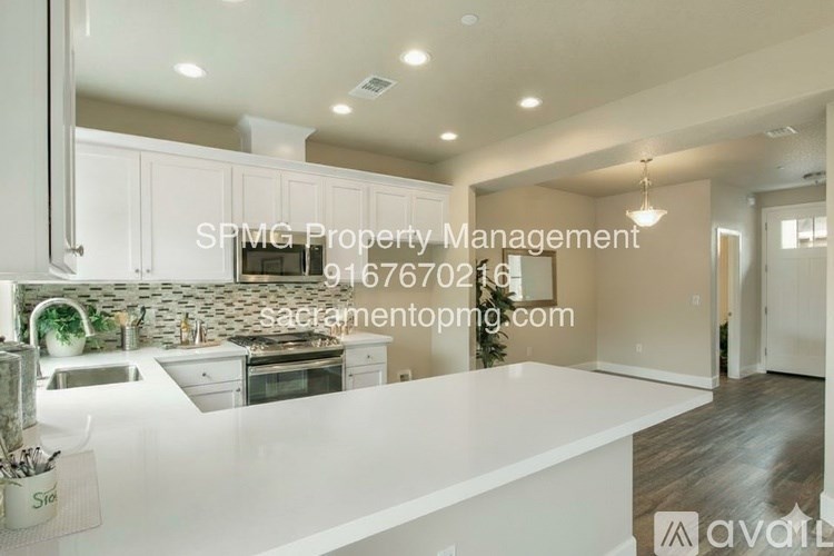 A modern kitchen with white countertops and cabinets, a stove, and a dining area in the background.