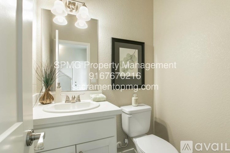 A bathroom with a toilet, sink, and mirror.