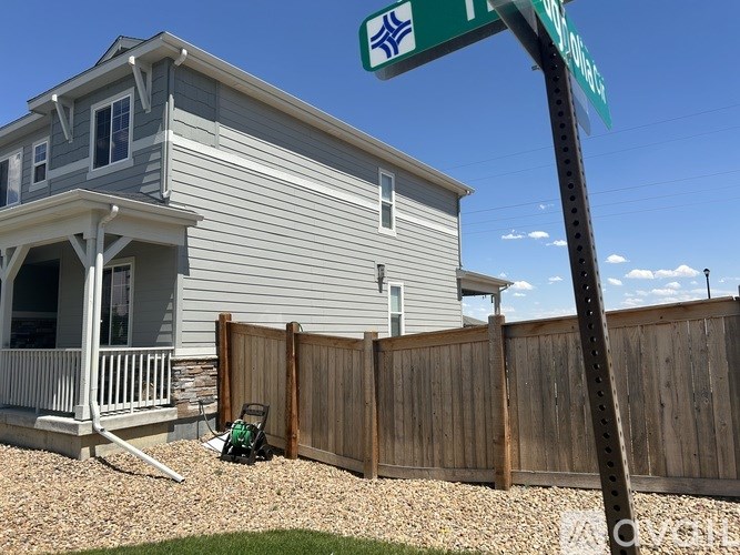A house with a porch and a fence in front of it.