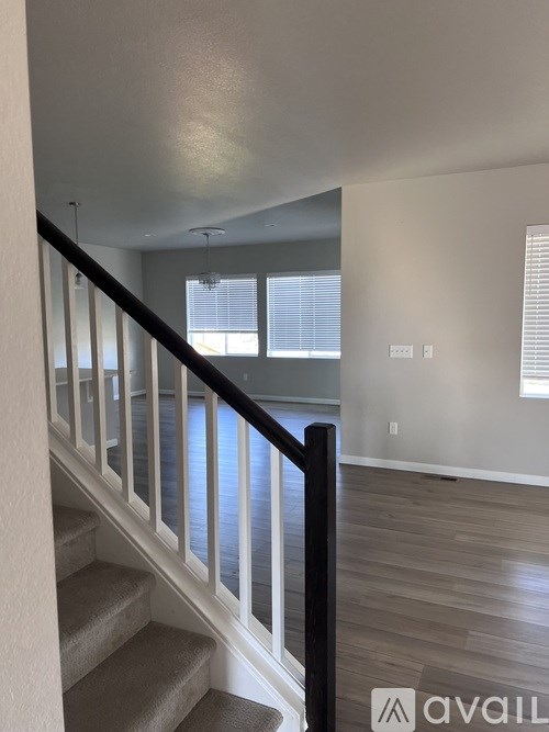 A staircase with a black railing leads to a bright room with a window.