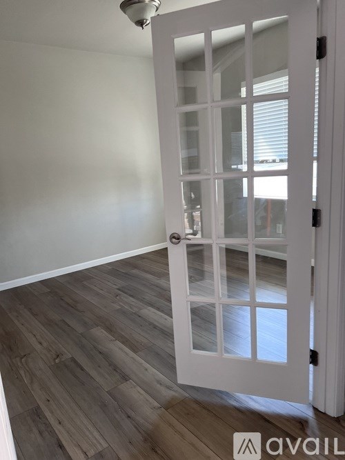 A white door with a glass panel and a silver handle is open.