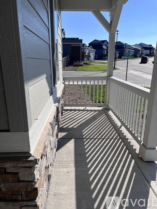 A white porch with a stone pillar and a white railing.