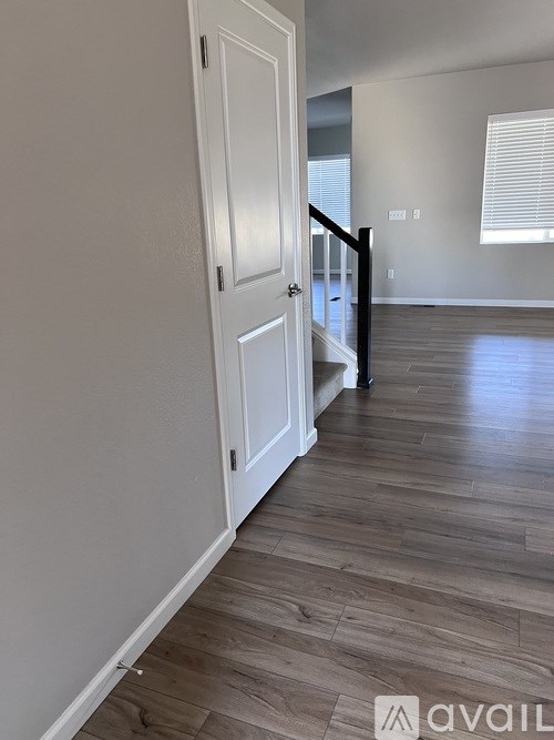 A hallway with a wooden floor and a white door.