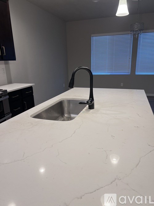 A kitchen with a marble countertop and a black faucet.