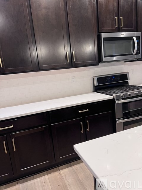 A kitchen with dark brown cabinets and a white countertop.
