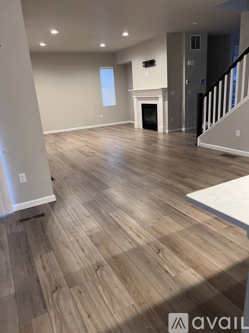 A spacious room with wooden flooring and a staircase.