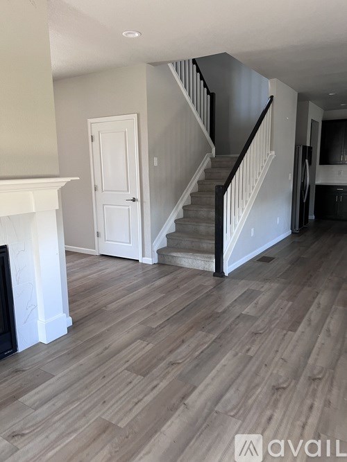 A living room with a fireplace and a staircase.